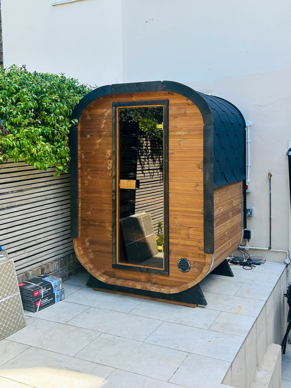 Camilla Compact outdoor sauna beside a garden patio