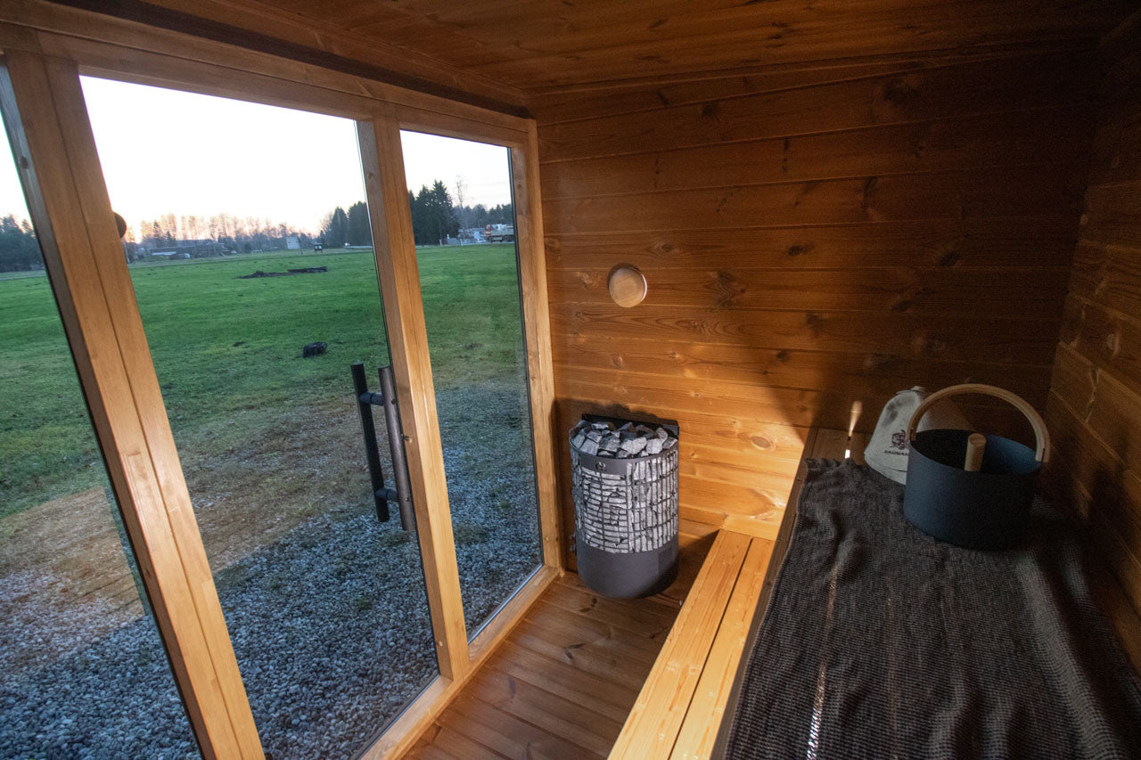 Interior view of the Leil Aris Lite sauna showing the two-level ThermoWood bench and heater position
