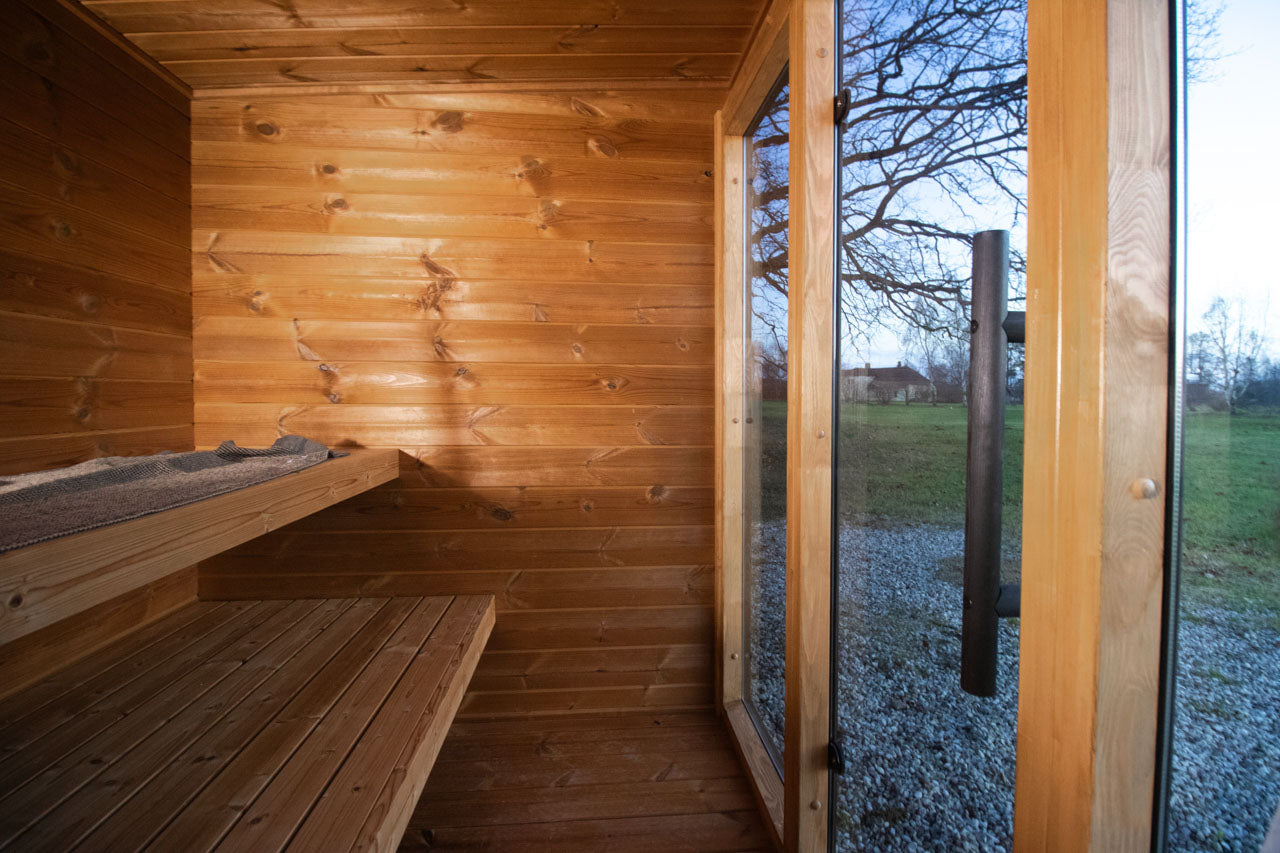 Leil Aris Lite interior corner showing the bench layout, ThermoWood walls and bronze glass front